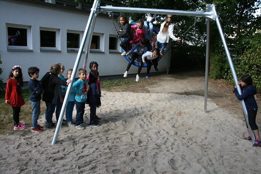 Die Schülerinnen und Schüler stehen bereits in einer Schlange, um die neue Schaukel auszuprobieren